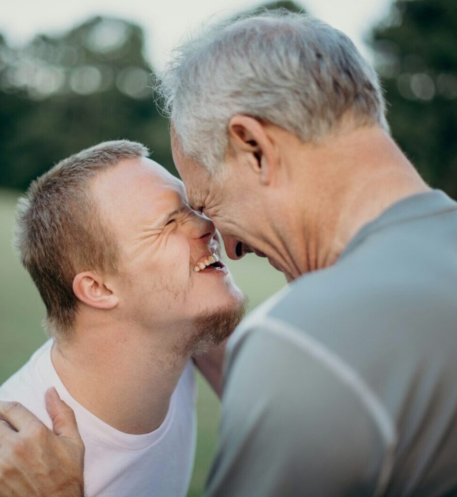 Person with learning disability smiling and touching heads with an older man