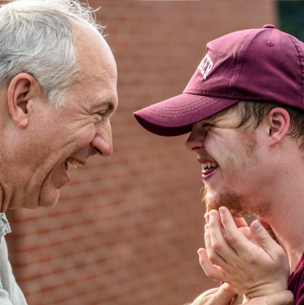 Person with learning disability smiling and facing an older man