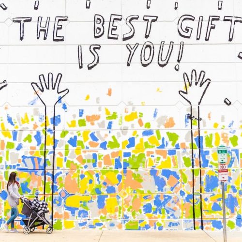 woman walking beside wall with the best gift is you graffiti