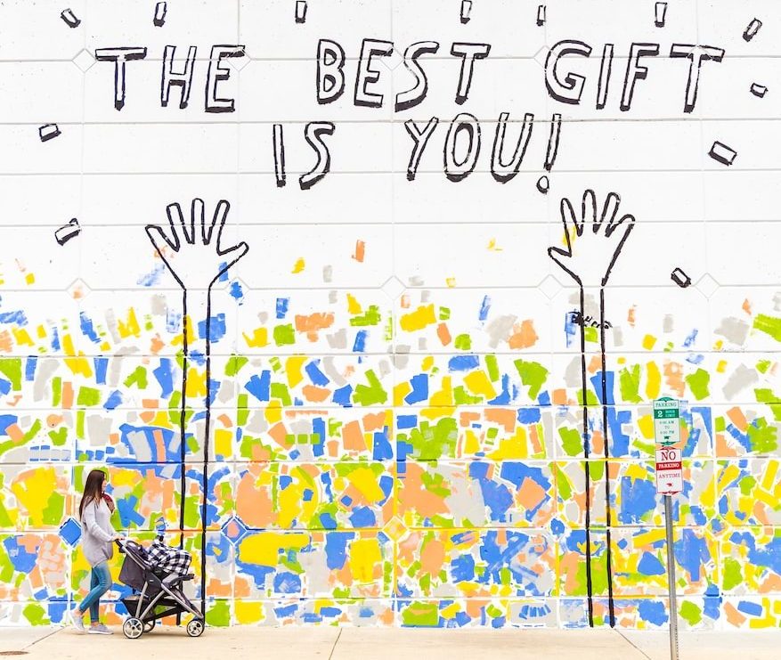 woman walking beside wall with the best gift is you graffiti