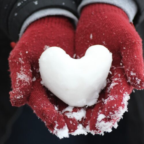 person holding heart-shaped snow