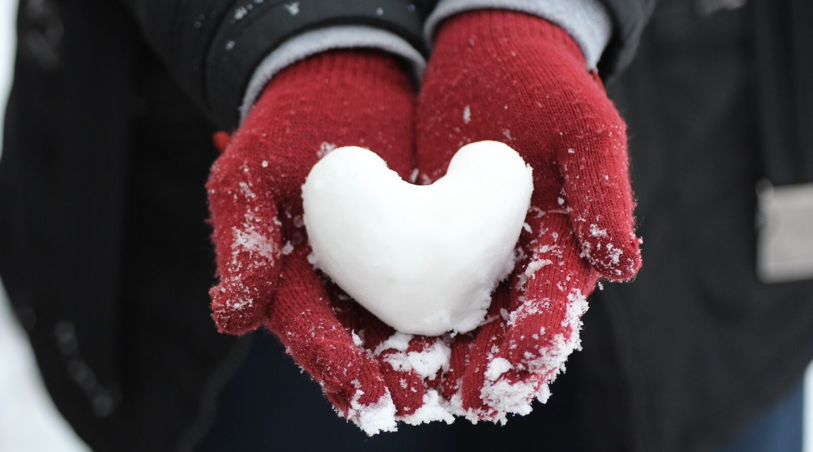 person holding heart-shaped snow