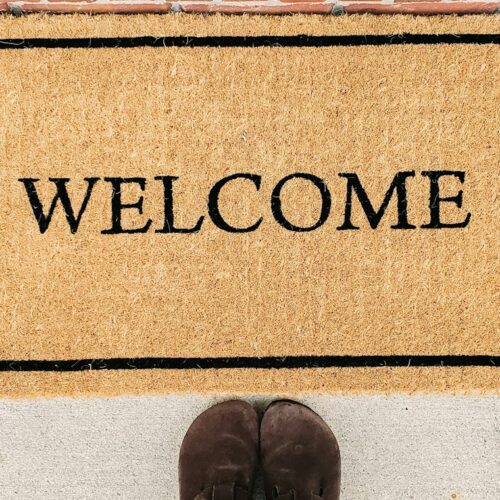 person in blue denim jeans standing on brown and black welcome area rug